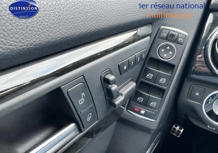 Détail intérieur montrant les commandes des vitres et rétroviseurs côté conducteur d’une Mercedes GLK noire 2014.