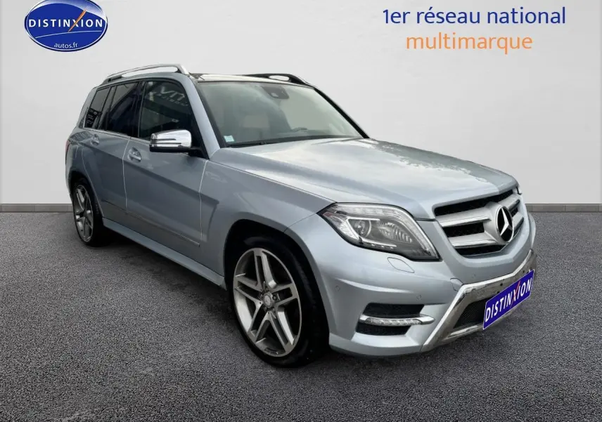 Vue 3/4 avant gauche d'un Mercedes GLK gris métallisé avec jantes alliage et barres de toit visibles.