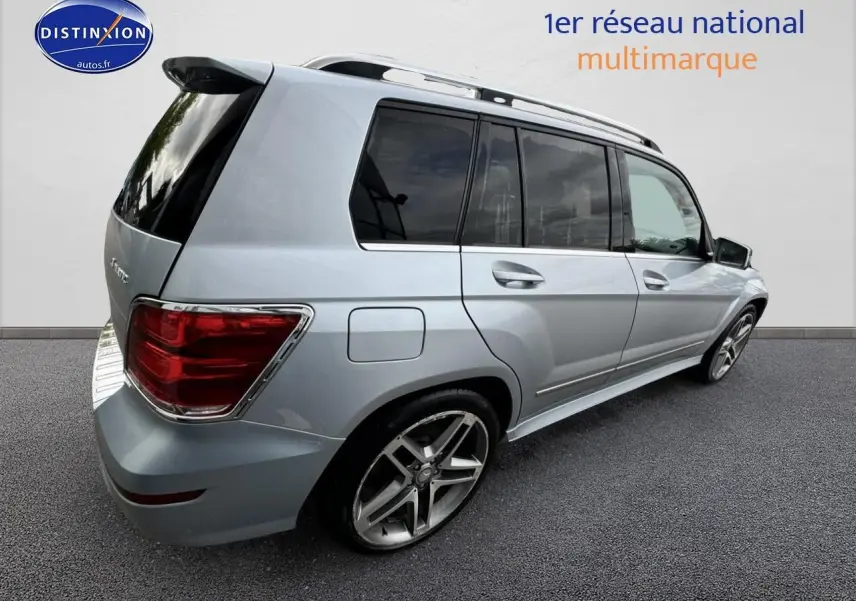 Vue 3/4 arrière droite d’un Mercedes GLK 350 4Matic gris métallisé avec barres de toit et vitres teintées.