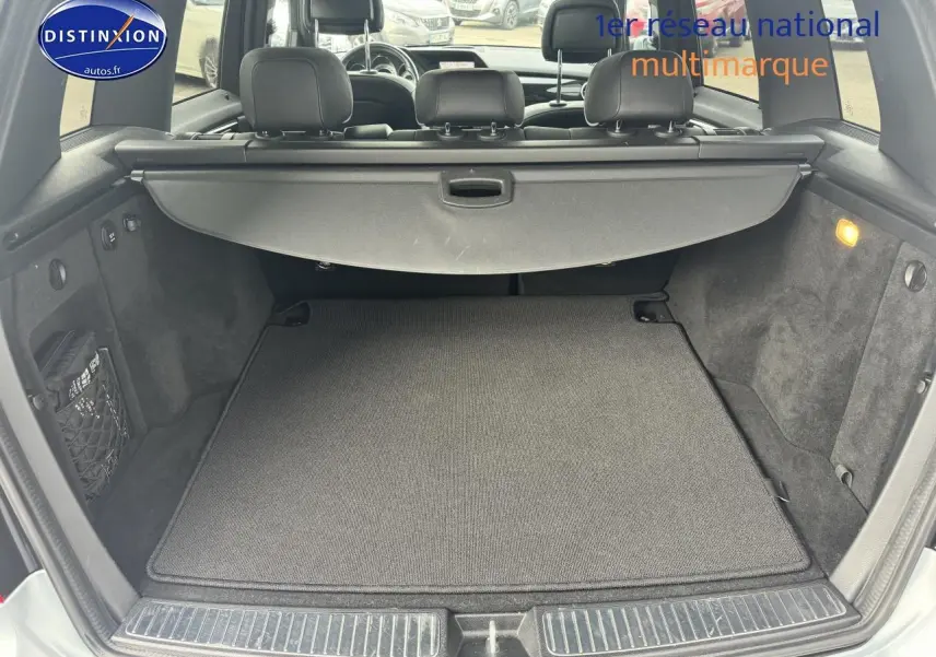 Coffre ouvert d’un Mercedes GLK noir, montrant la tablette cache-bagages et l’espace de chargement vide.