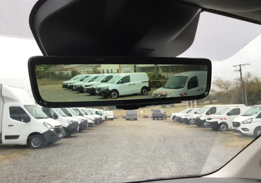 Vue depuis l'intérieur du Peugeot Expert gris titane, avec le rétroviseur affichant plusieurs utilitaires blancs en rangée.