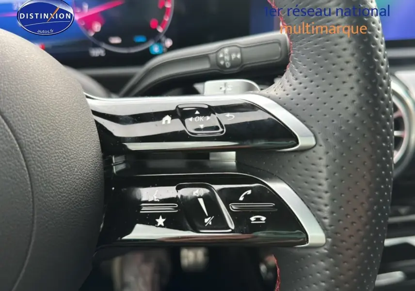 Gros plan sur les commandes multifonctions en cuir perforé du volant de la Mercedes Classe A 180 AMG Line 2024.