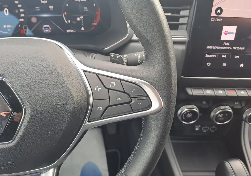 Gros plan sur le volant noir du Renault Captur 2022 avec commandes intégrées et tableau de bord numérique en arrière-plan.