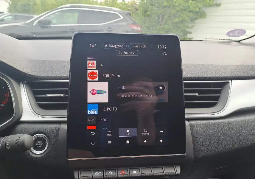 Vue intérieure centrée sur l'écran tactile multimédia du Renault Captur gris cassiopée avec toit noir, affichant les radios.
