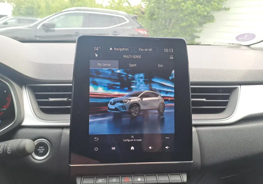 Écran central affichant une Renault Captur gris Cassiopée avec toit noir en vue 3/4 avant dynamique.