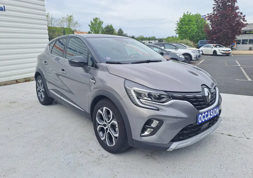 Renault Captur gris cassiopée avec toit noir, vue 3/4 avant droit, sur parking extérieur avec plaque occasion.
