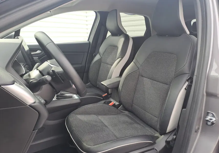 Vue intérieure côté conducteur du Renault Captur 2022, sièges tissu noir avec surpiqûres claires et garniture grise.