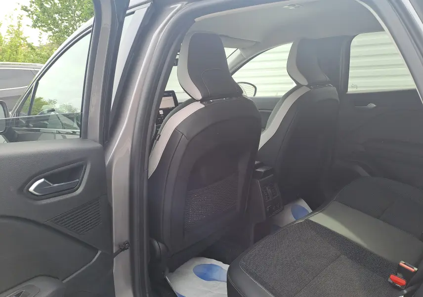 Vue intérieure arrière côté gauche du Renault Captur gris Cassiopée avec sièges noirs et toit noir visible.