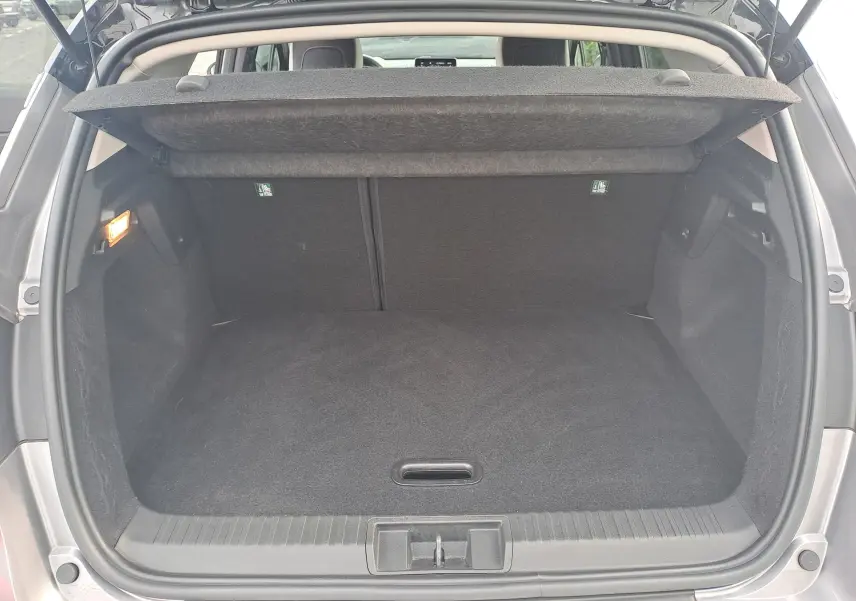 Coffre ouvert vu de l'arrière du Renault Captur gris Cassiopée avec toit noir, montrant l'espace de chargement vide et le cache-bagages relevé.