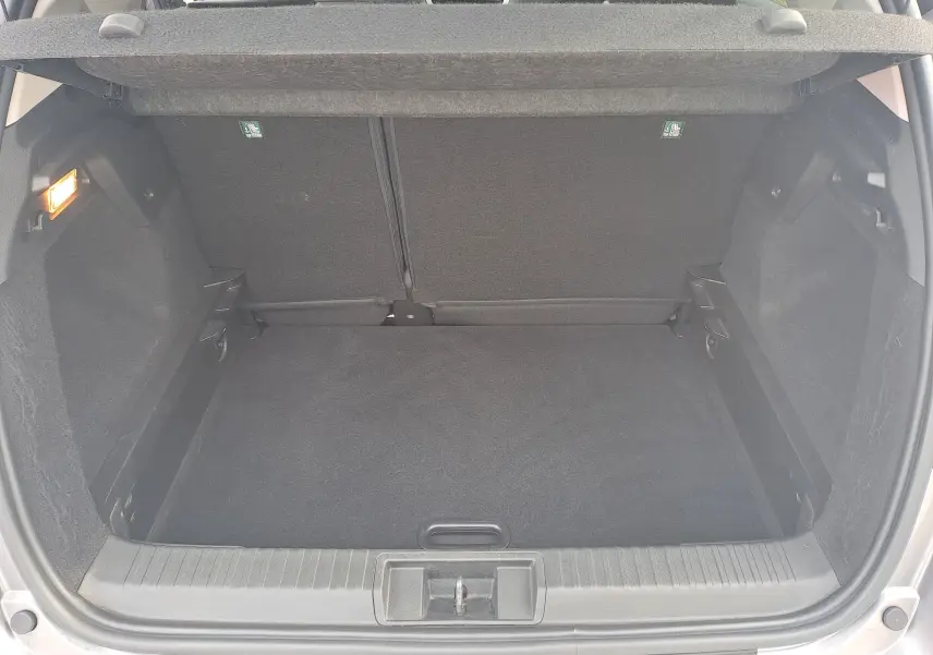 Coffre ouvert vu de l'arrière du Renault Captur gris Cassiopée avec intérieur noir et tapis de sol propre.