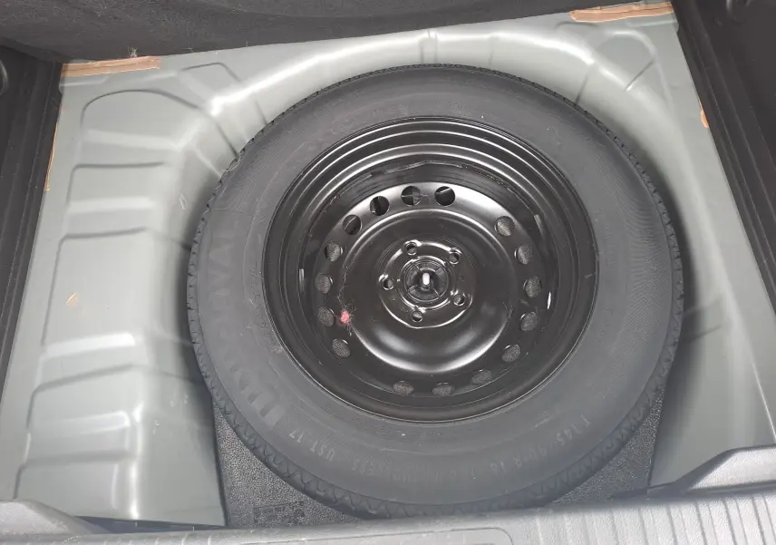 Vue plongeante sur la roue de secours noire dans le coffre gris d’un Renault Captur 2022.