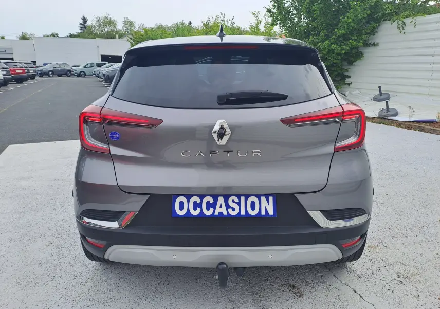 Vue arrière d’un Renault Captur gris Cassiopée avec toit noir, feux LED et attelage visible sur parking.
