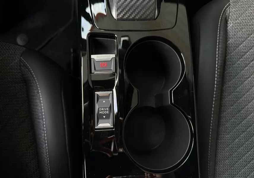 Vue plongeante sur la console centrale noire brillante du Peugeot 2008 avec boutons frein à main électronique et mode de conduite.