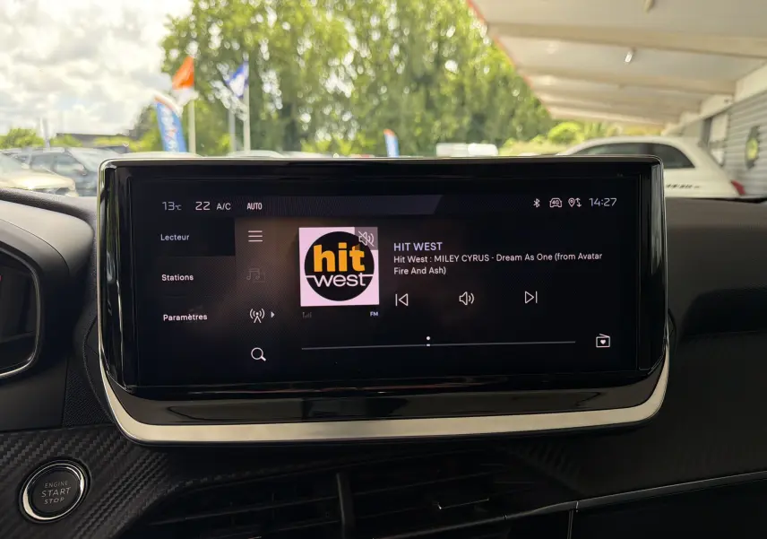 Écran tactile central du Peugeot 2008 1.2 130 EAT8 Allure affichant la radio Hit West, intérieur noir.