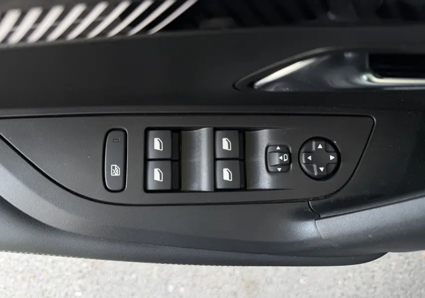 Vue rapprochée des commandes de lève-vitres et réglage des rétroviseurs côté conducteur d’un Peugeot 2008 gris Sellenium.