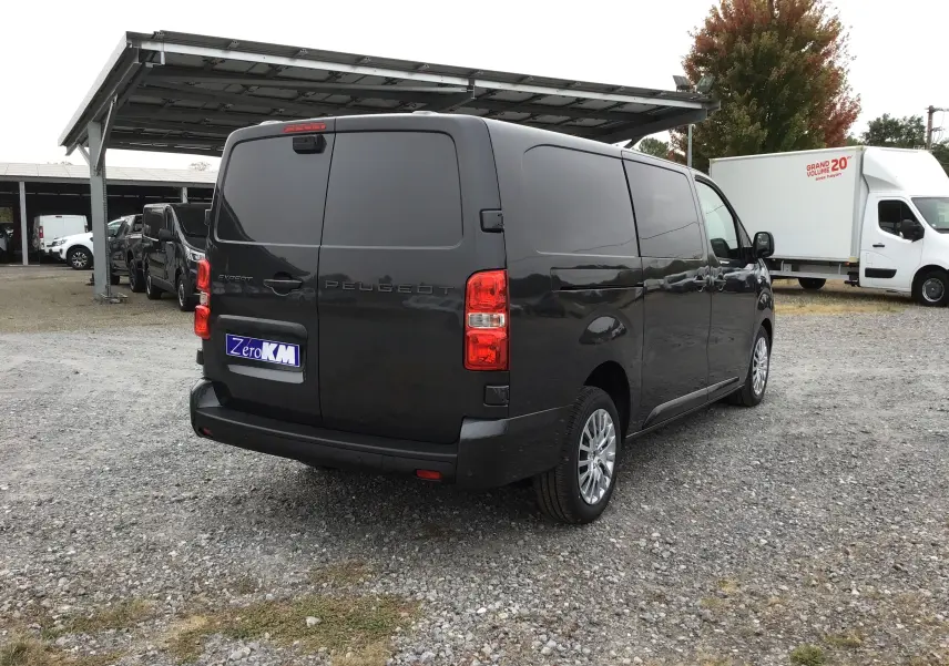 Vue 3/4 arrière droite d'un Peugeot Expert gris titane, fourgon fermé avec vitres teintées et feux arrière rouges.