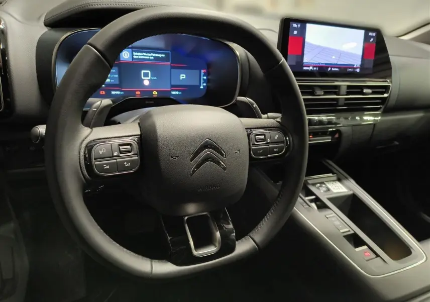 Vue rapprochée du volant noir et du tableau de bord numérique du Citroën C5 Aircross 2025 avec écran tactile central.