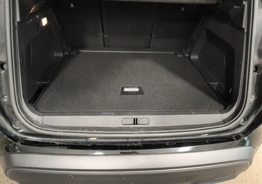 Coffre ouvert vu de l'arrière d'un Citroën C5 Aircross 2025 noir Perla avec seuil de chargement et éclairage intérieur.