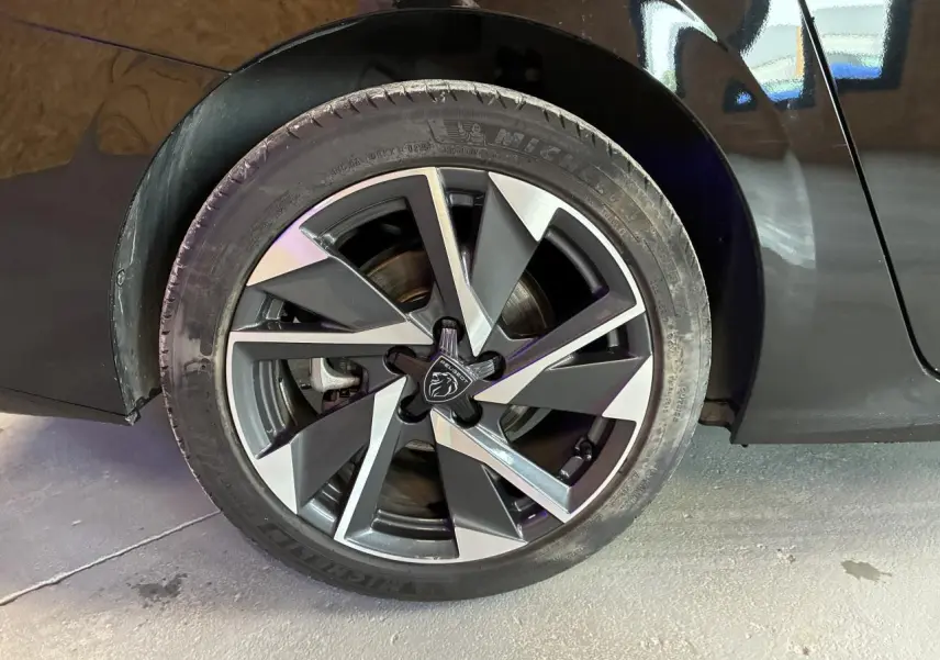 Gros plan sur la jante alliage 17'' Halong diamantée noire et argentée du côté arrière droit d'une Peugeot 308 SW noire.