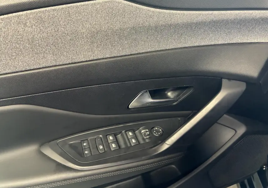 Panneau de porte intérieur côté conducteur noir avec commandes électriques et poignée sur Peugeot 308 SW 2024.