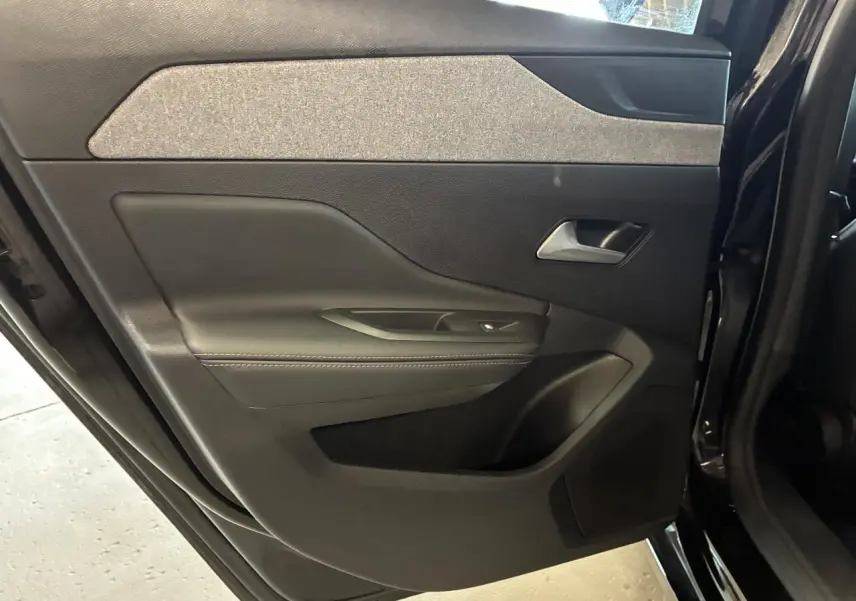 Vue intérieure côté gauche de la porte arrière noire du Peugeot 308 SW 2024 avec habillage tissu et plastique.