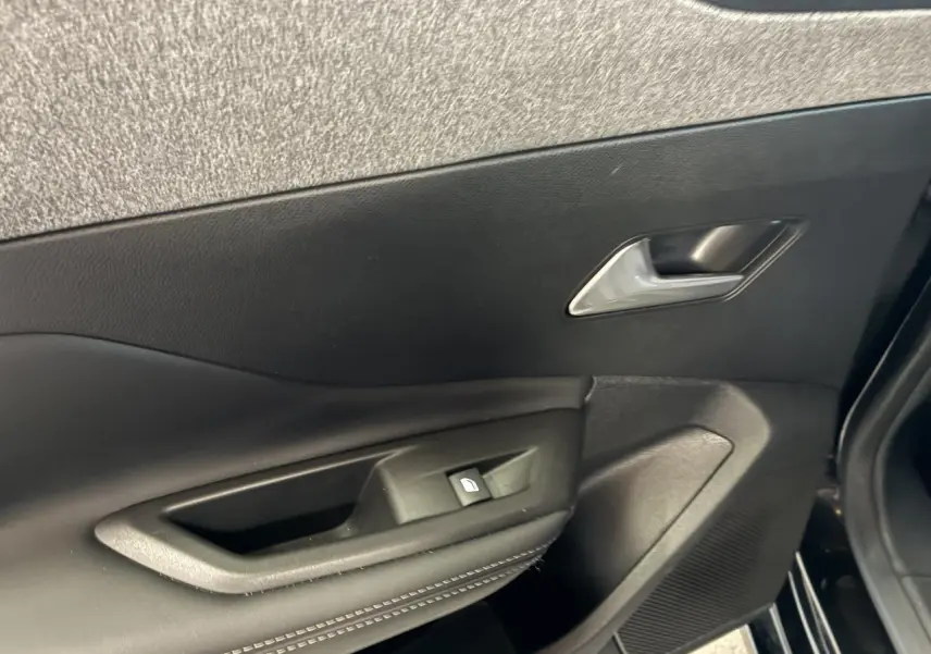Gros plan sur la porte intérieure côté gauche noire avec poignée et commande de lève-vitre de la Peugeot 308 SW 2024.