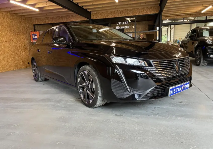 Peugeot 308 SW noire vue en 3/4 avant droit dans un garage avec jantes alliage et calandre chromée.