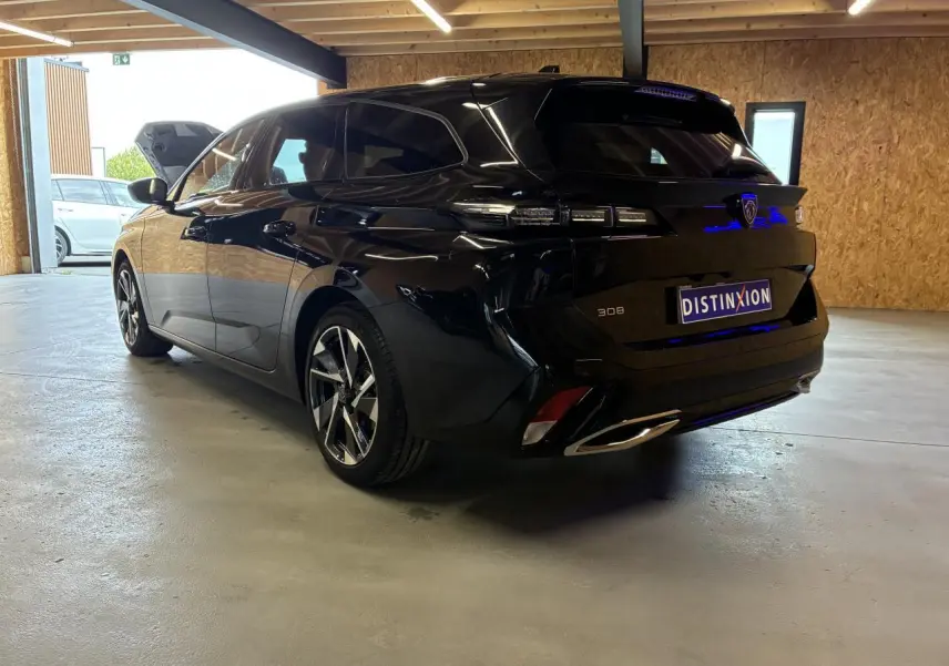 Peugeot 308 SW noire vue 3/4 arrière droit dans un garage, avec feux arrière LED et jantes alliage 17 pouces.