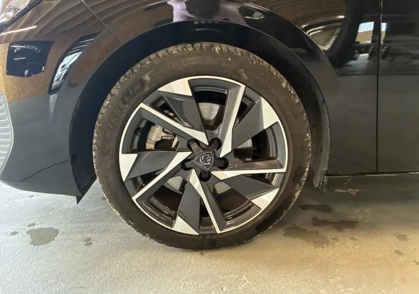 Gros plan sur la roue avant gauche noire d'une Peugeot 308 SW 2024 avec jante alliage 17'' Halong diamantée.