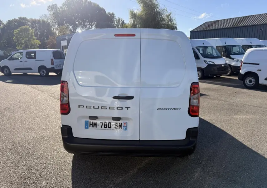 Vue arrière d’un utilitaire blanc Peugeot Partner Taille M, portes battantes fermées, plaque d’immatriculation visible.