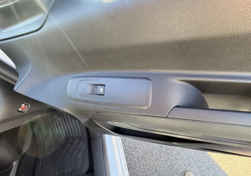 Vue intérieure sur la porte côté conducteur du Peugeot Partner blanc, avec commande de vitre électrique visible.
