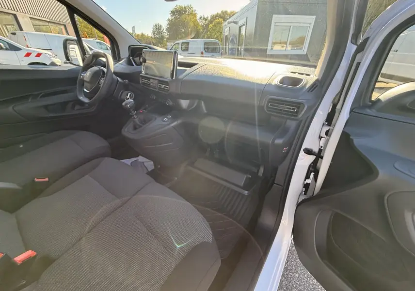Vue intérieure côté passager du Peugeot Partner blanc 2026, montrant sièges, tableau de bord et volant multifonctions.