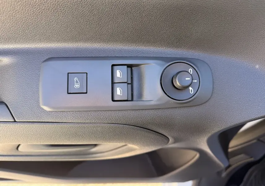 Détail des commandes de réglage des rétroviseurs et des vitres sur la porte côté conducteur d’un Peugeot Partner blanc.
