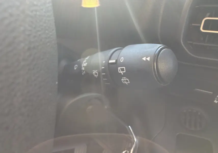 Gros plan sur la commande d’essuie-glace à gauche du volant dans l’habitacle du Peugeot Partner blanc.
