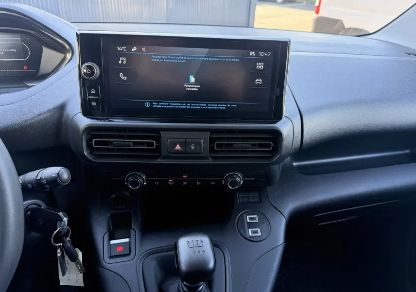 Vue intérieure du tableau de bord du Peugeot Partner blanc 2026, avec écran tactile central et levier de vitesses manuel.