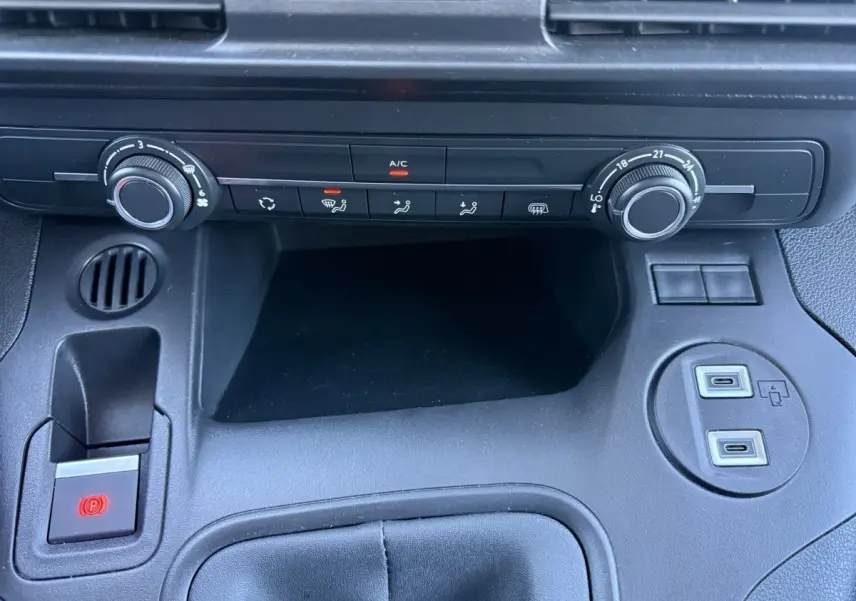 Vue rapprochée de la console centrale noire du Peugeot Partner 2026 avec commandes climatisation et ports USB visibles.