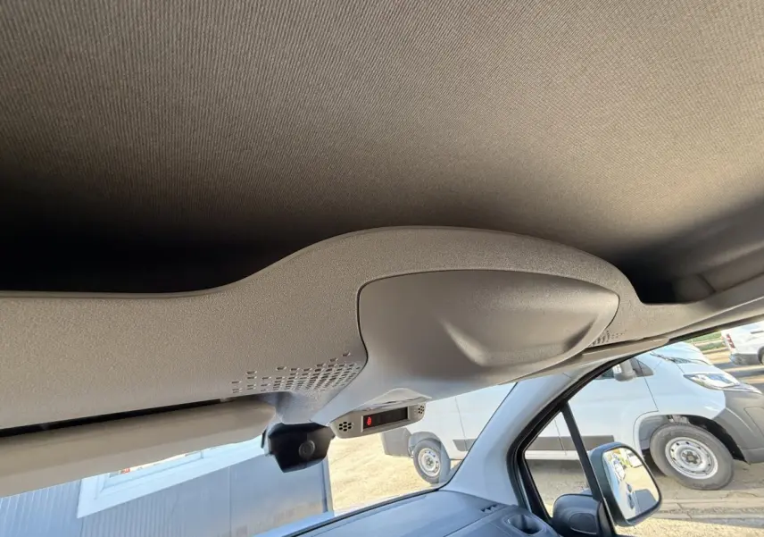 Vue intérieure du plafond et pare-soleil côté conducteur du Peugeot Partner blanc, avec rétroviseur et partie du tableau de bord visibles.