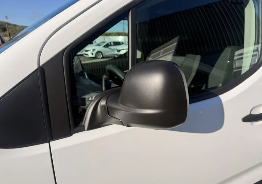 Rétroviseur noir côté conducteur du Peugeot Partner blanc, vue rapprochée sur la porte avant gauche.