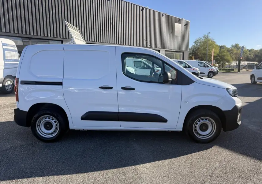Vue de profil côté gauche d’un utilitaire Peugeot Partner blanc avec protections noires sur porte et roues acier.