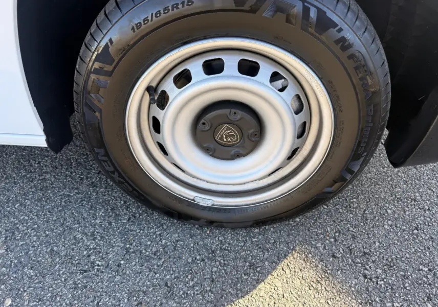 Gros plan sur la roue avant gauche du Peugeot Partner blanc, mettant en valeur la jante acier et le pneu Nexen.