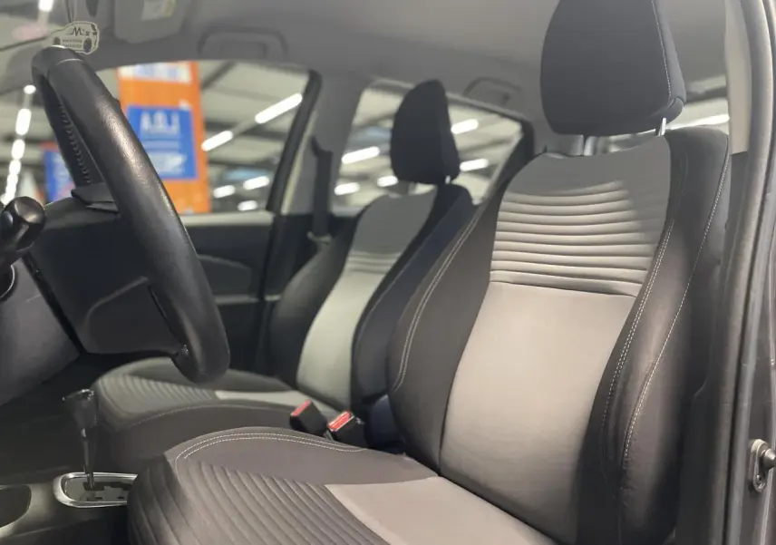 Vue intérieure côté conducteur de la Toyota Yaris hybride 2020, sièges tissu gris clair et foncé, volant cuir noir.
