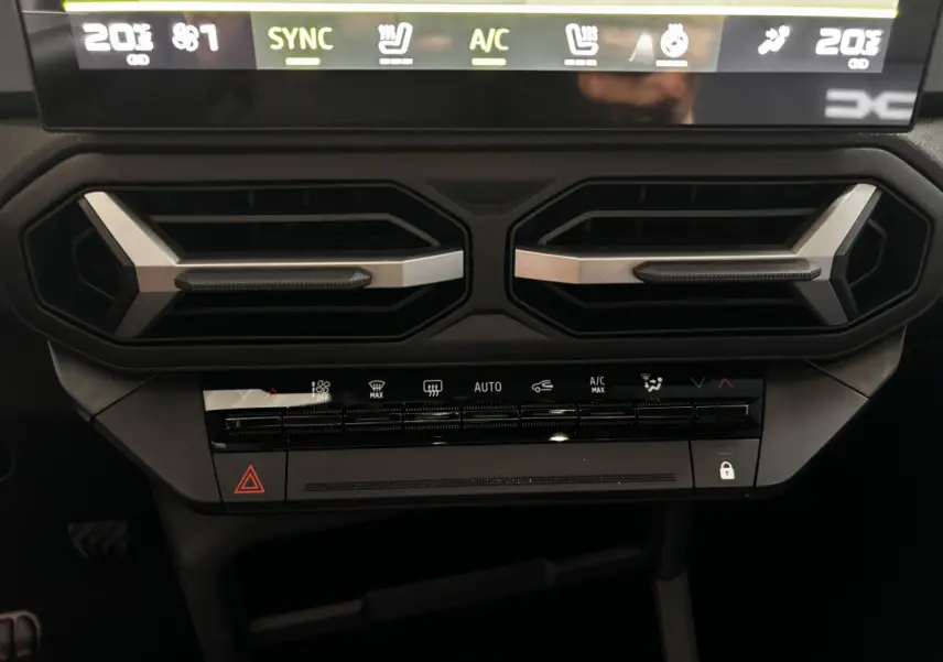 Détail du tableau de bord central du Dacia Bigster 2025 gris foncé, avec commandes climatisation et aérateurs hexagonaux.