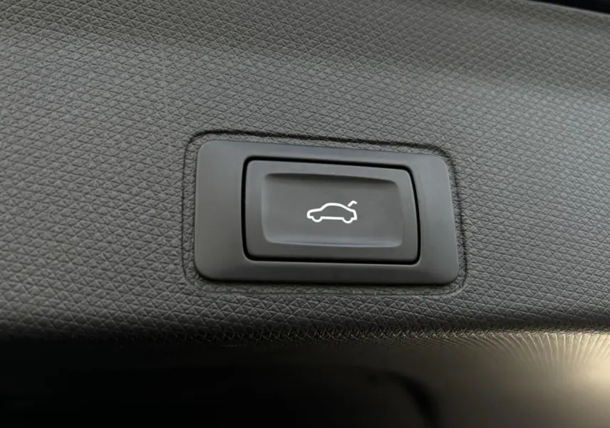 Bouton noir d'ouverture électrique du hayon sur panneau intérieur texturé du coffre du CUPRA TERRAMAR Dark Void.