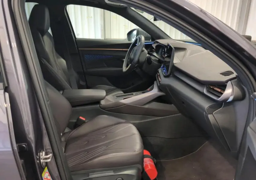 Intérieur avant du CUPRA TERRAMAR 2024 en cuir noir avec tableau de bord texturé et éclairage d'ambiance bleu visible.