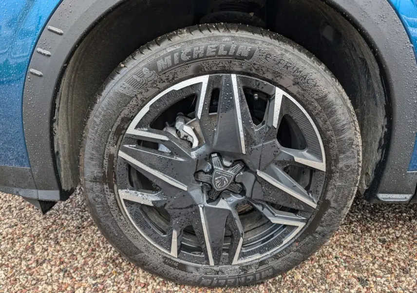 Gros plan sur la jante alliage 19'' diamantée noire du côté avant gauche d’un Peugeot 3008 bleu métallisé.