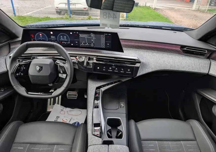 Vue intérieure avant du Peugeot 3008 2025 hybride, avec tableau de bord numérique panoramique et sellerie tissu gris.