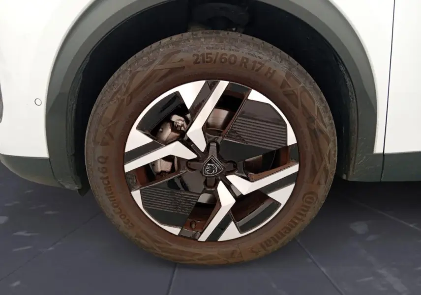 Gros plan sur la roue avant droite du Peugeot 2008 blanc, jante alliage 17 pouces au design moderne bicolore.