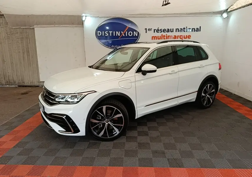 Volkswagen Tiguan 1.4 eHybrid blanc en 3/4 avant droit, avec jantes noires et détails R-Line visibles.