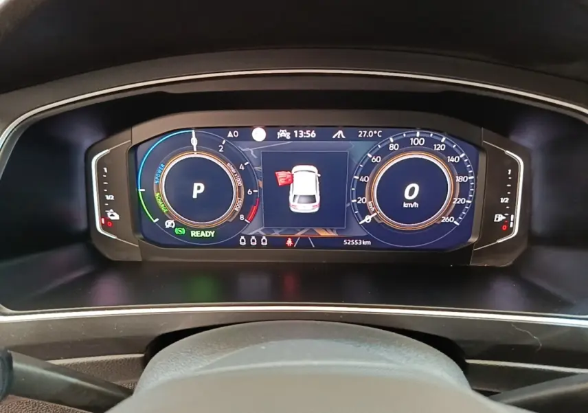 Vue rapprochée du tableau de bord numérique du Volkswagen Tiguan blanc, affichant vitesse, régime et alertes.