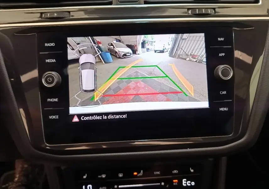 Écran tactile central montrant la caméra de recul avec guidage dynamique sur un Volkswagen Tiguan blanc.